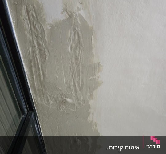 תיקון קיר עם חומר איטום ליד חלון זכוכית.